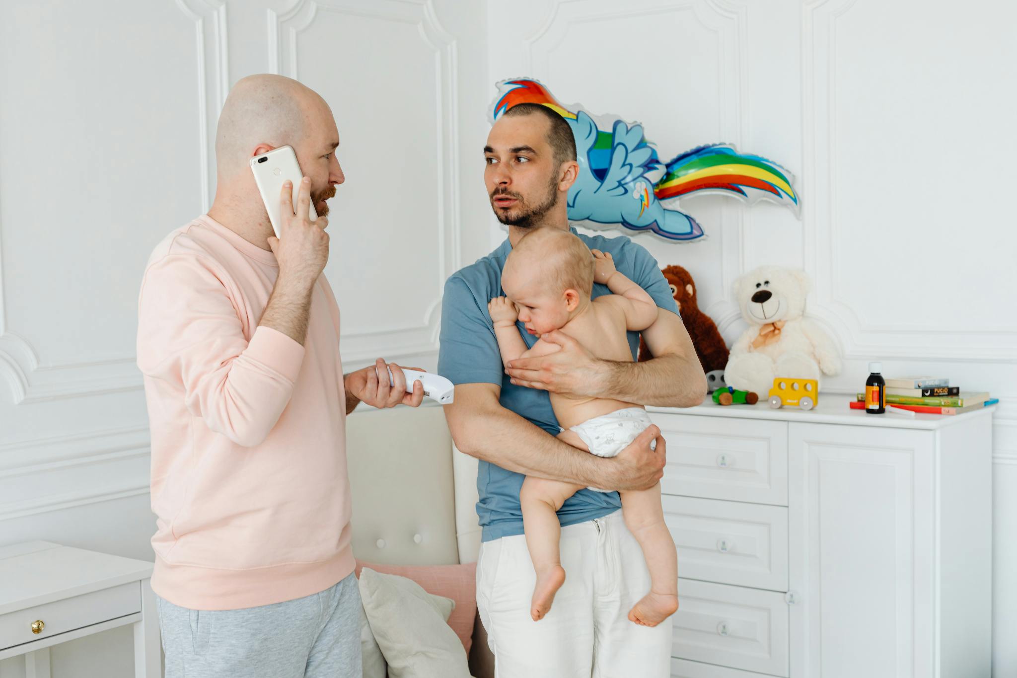 A heartwarming scene of two fathers lovingly caring for their baby indoors.