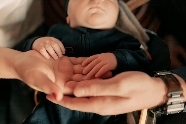 Close-up of parents holding their baby's hands, symbolizing love and protection.