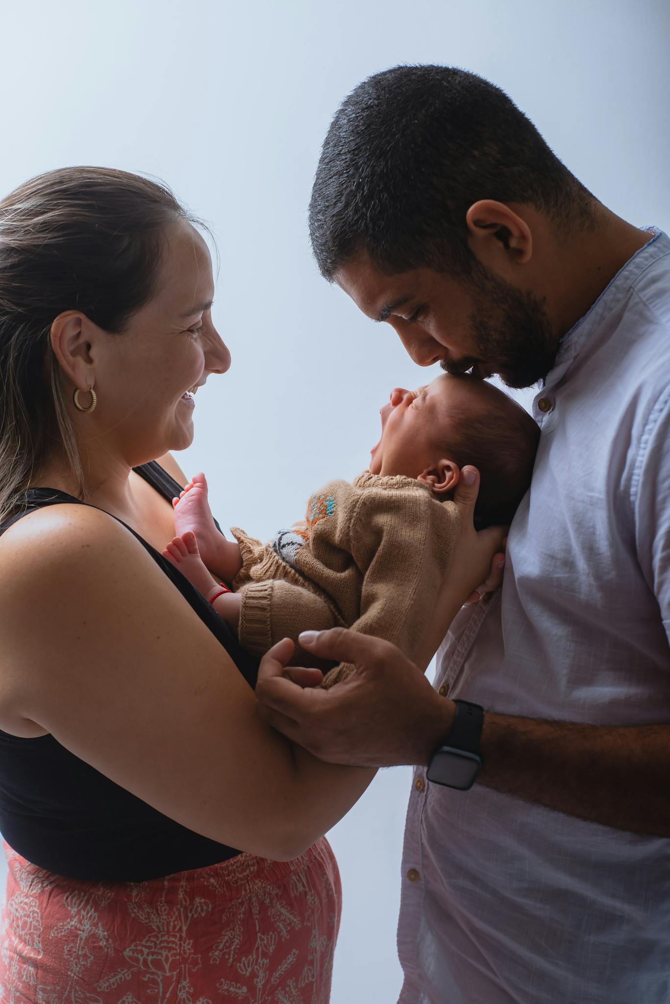 Heartwarming scene of parents lovingly holding their newborn baby indoors.